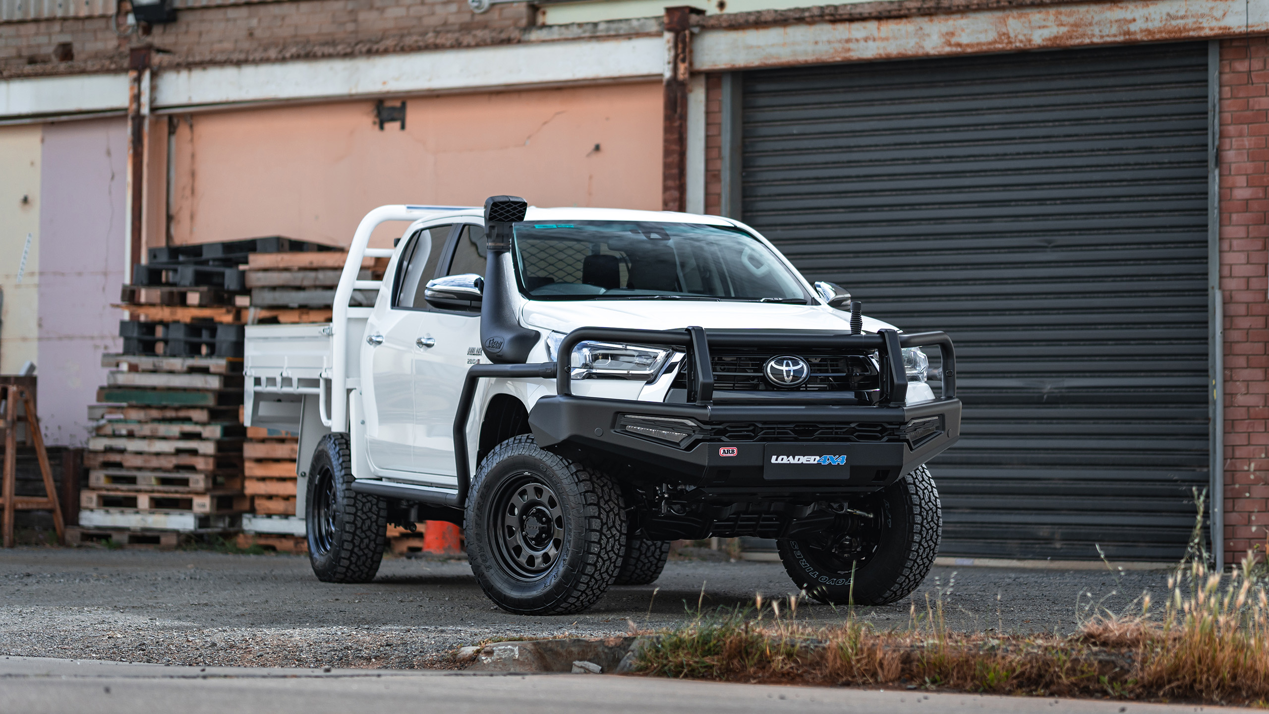 Ranger AT steel wheels on white Toyota HiLux in front of industrial buildings Ranger AT steel wheels on white Toyota HiLux in front of industrial buildings