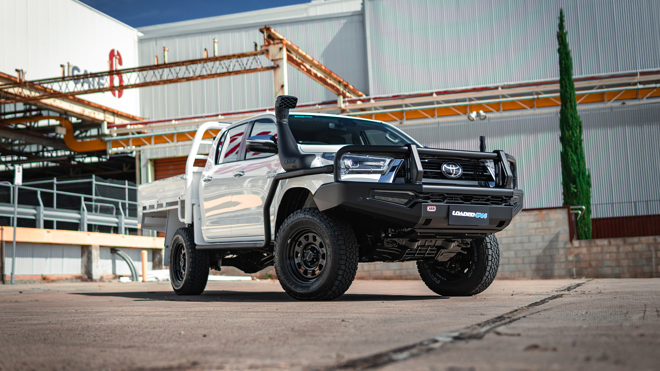 Ranger AT steel wheels on white Toyota HiLux in industrial area Ranger AT steel wheels on white Toyota HiLux in industrial area