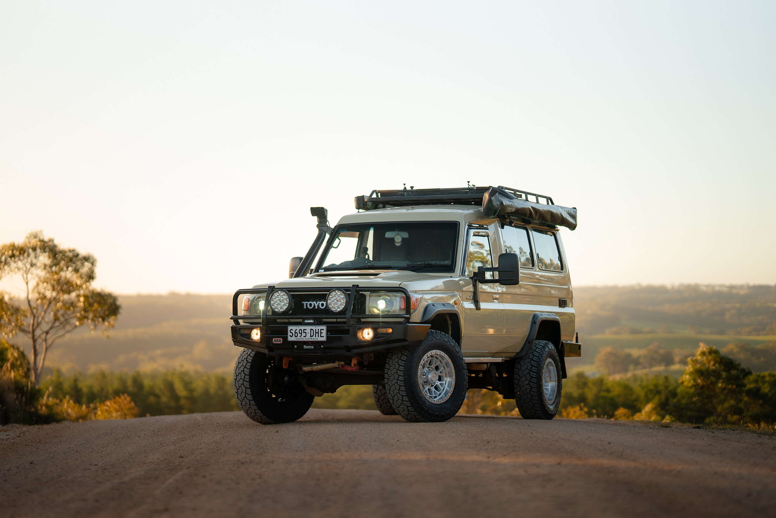 CSA Thunder deep dish machined wheels on sandy LandCruiser 78 Series on gravel road at the top of a hill with scenic view over the bush